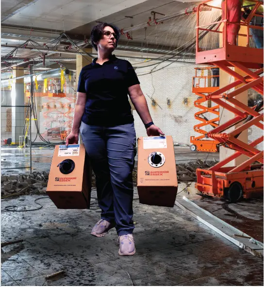 Elizabeth holding boxes of cables in a construction site